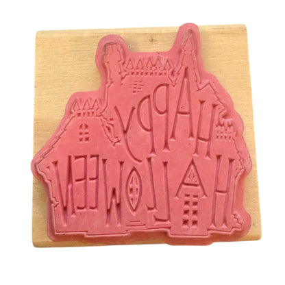 Pink rubber stamp shaped like a house on a wooden block