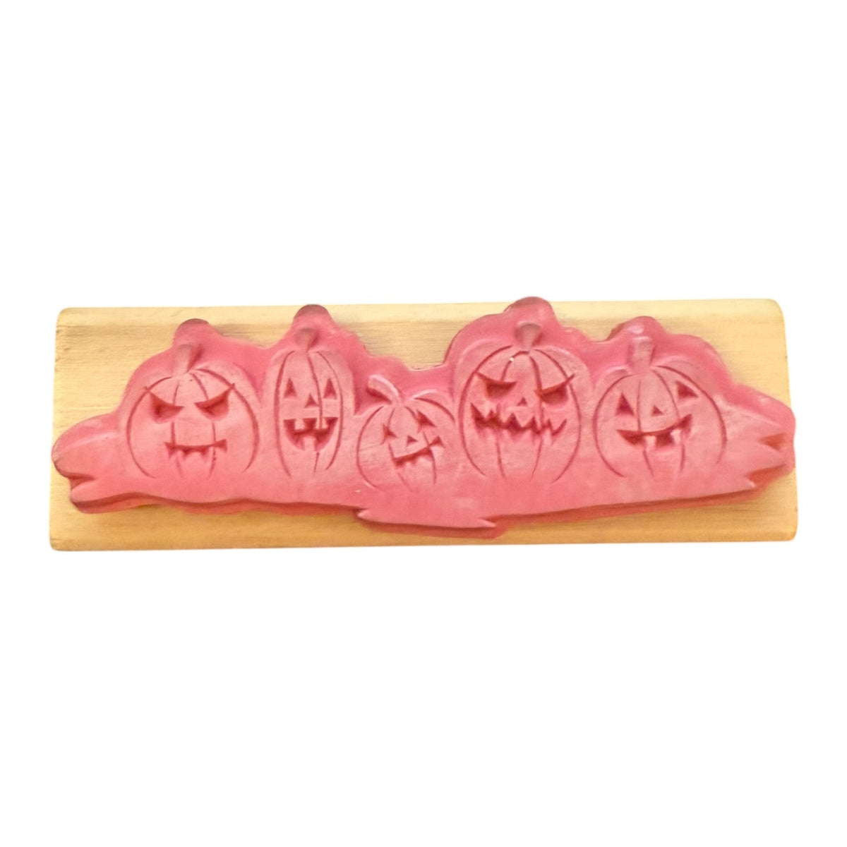 Pink pumpkin-shaped rubber stamp on a wooden board with a white background