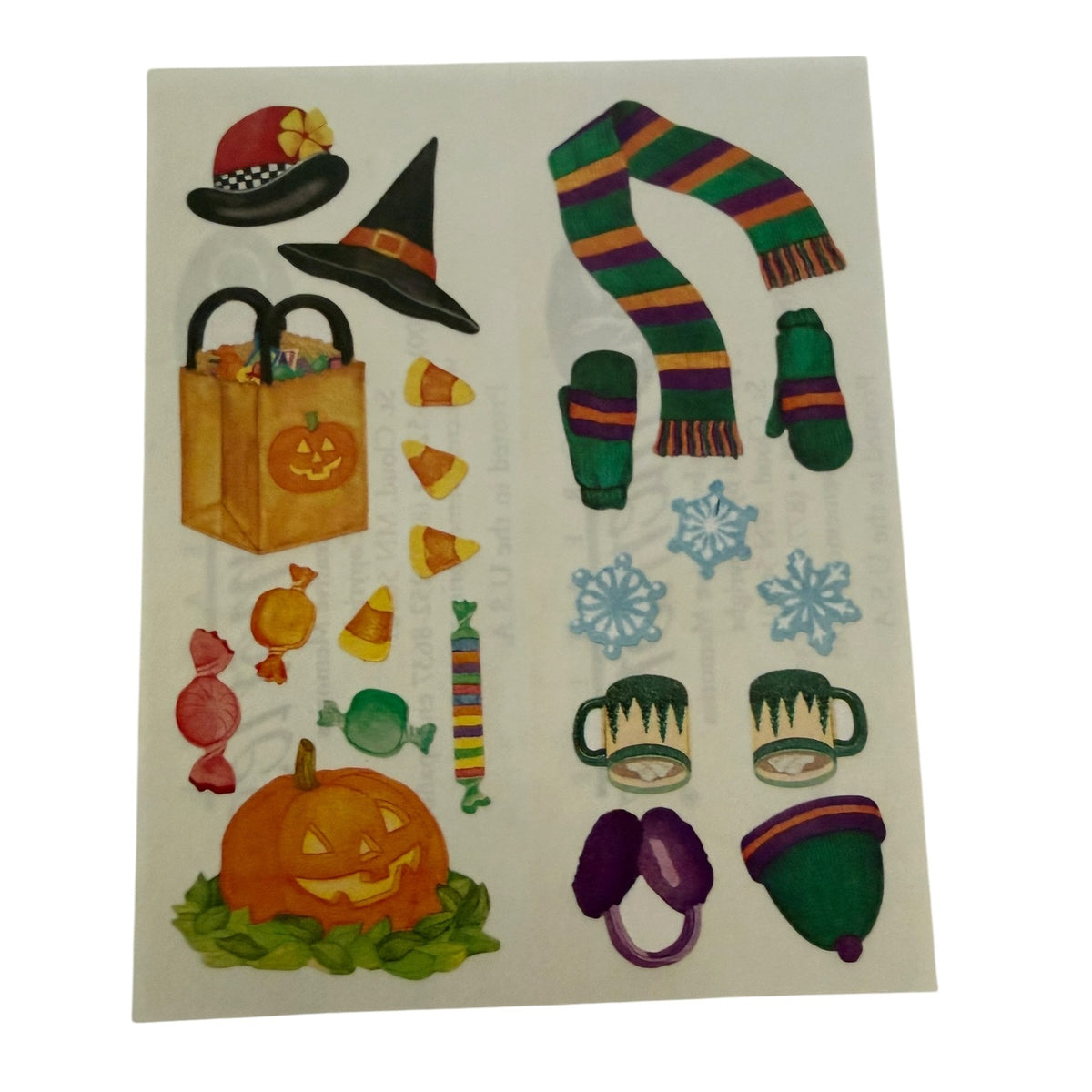 A sheet of Halloween-themed stickers on a white background, featuring a witch hat, striped scarf and mittens, candy corn, jack-o'-lantern, shopping bag, snowflakes, mugs, and earmuffs.