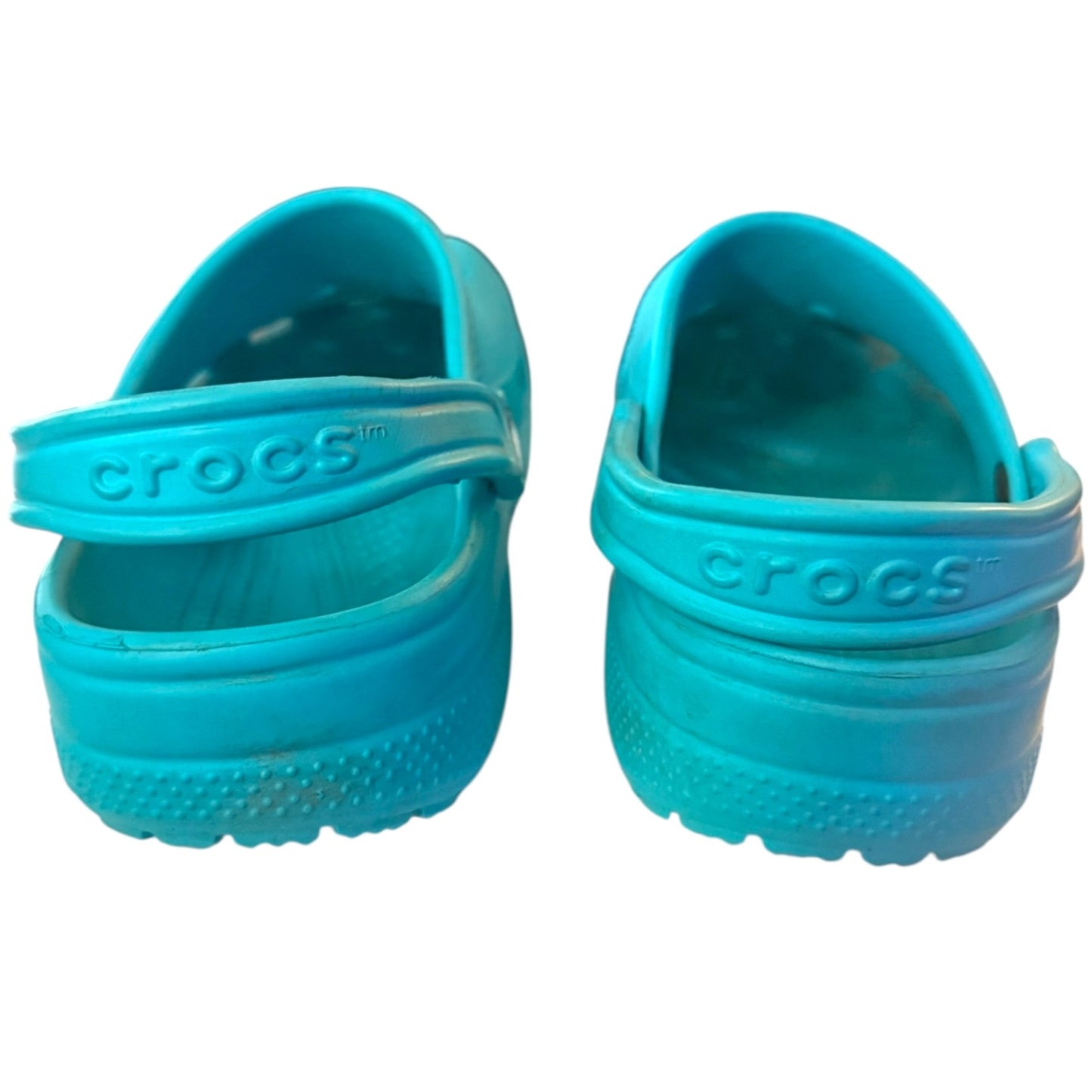 Back of a Pair of turquoise Crocs sandals on a white background