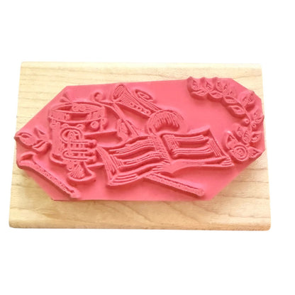 A pink rubber stamp mounted on a light-colored wooden block against a white background.