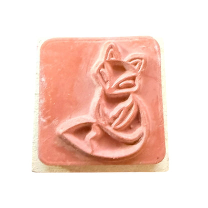 Rubber stamp of a fox design embossed on a light wood block shown against a plain white background.
