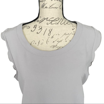 A light gray top with ruffled cap sleeves, displayed on a vintage-style fabric dress form with cursive script print.