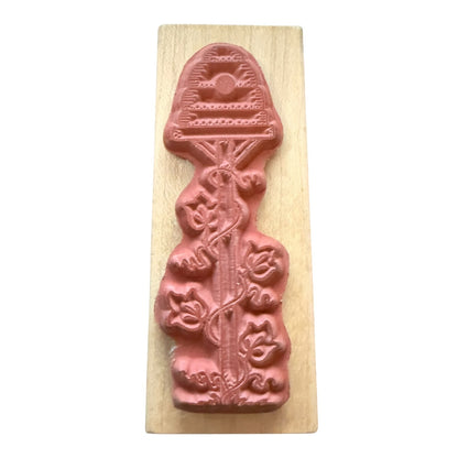 A terracotta-colored Rubber stamp on a wood block with a white background. 
