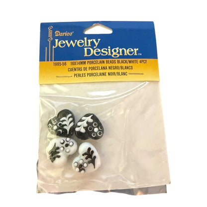 A package of four 16x14mm porcelain beads from Darico Jewelry Designer, featuring black and white floral heart-shaped beads in a clear plastic bag with a blue and yellow header card.