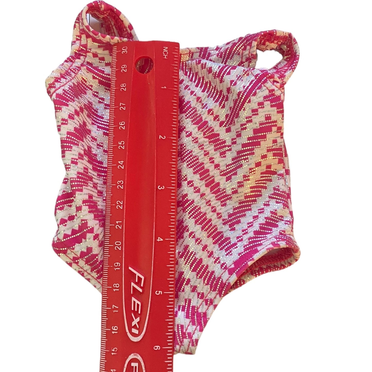 Pink and white patterned leotard with a red ruler for size reference on a white background