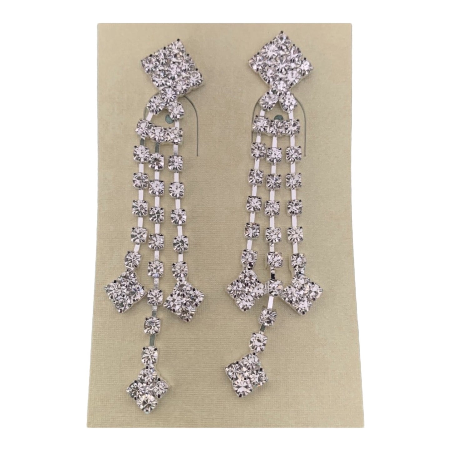 A pair of silver-toned dangle earrings embellished with clear rhinestones in a geometric, multi-tiered design, shown on a beige card against a plain white background.