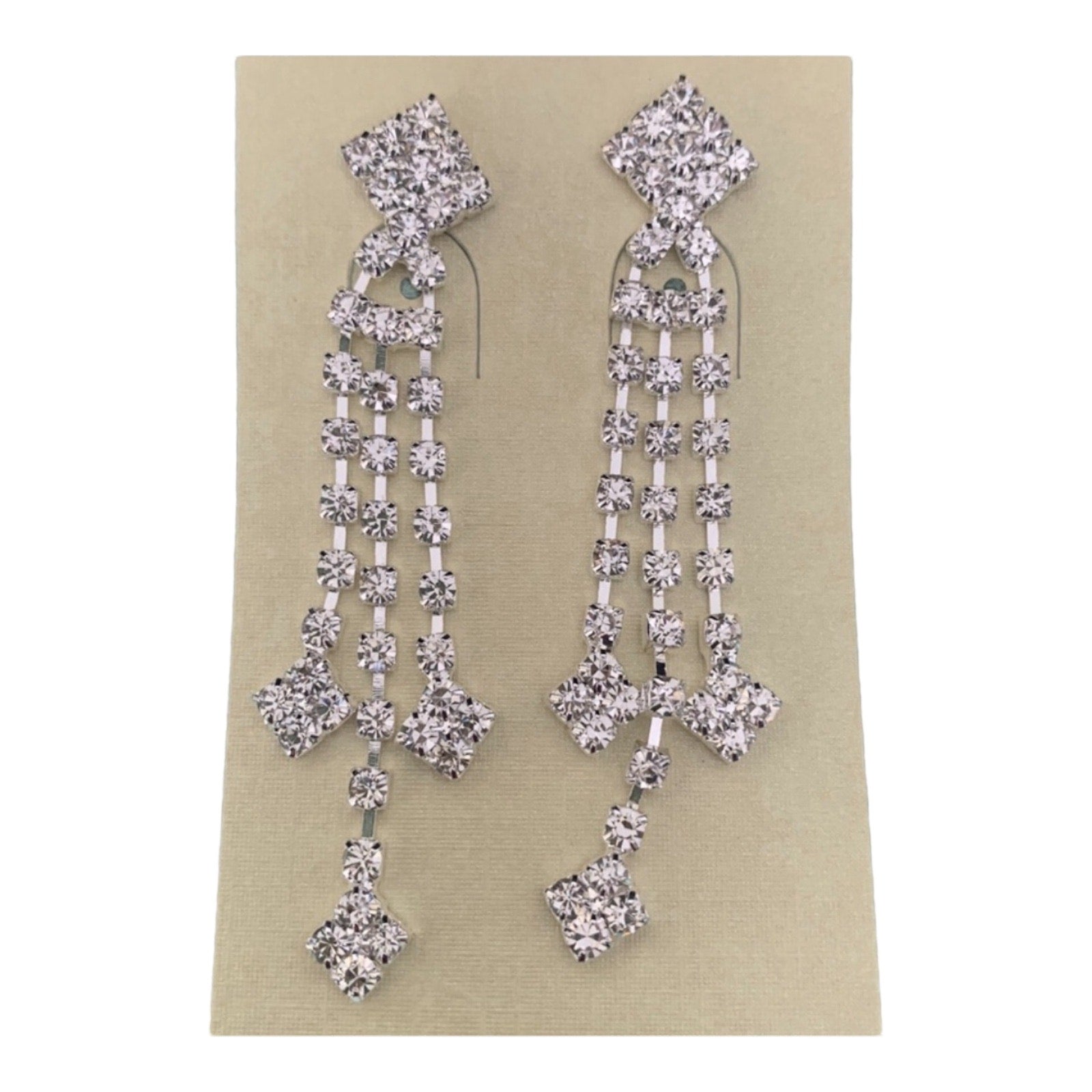 A pair of silver-toned dangle earrings embellished with clear rhinestones in a geometric, multi-tiered design, shown on a beige card against a plain white background.