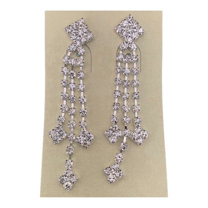 A pair of silver-toned dangle earrings embellished with clear rhinestones in a geometric, multi-tiered design, shown on a beige card against a plain white background.