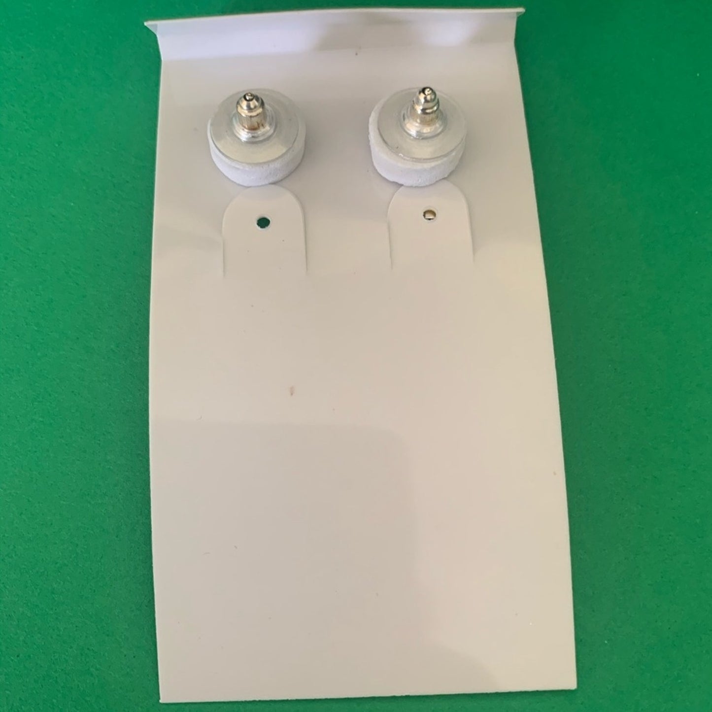 Back of a Pair of earrings on a white card with a green background