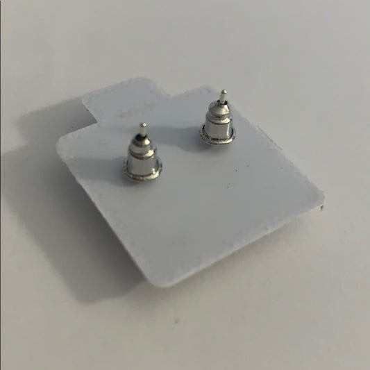 A pair of small silver stud earrings mounted on a white display card, photographed on a plain light gray surface.