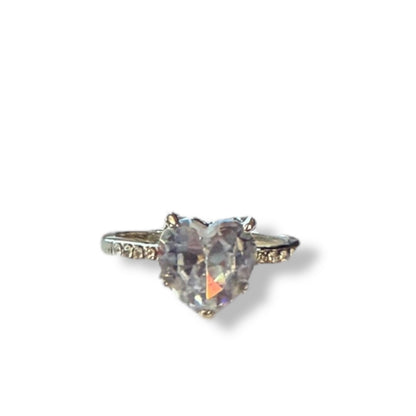 A heart-shaped iridescent gemstone ring set in a silver-toned band with small accent stones on either side, shown against a plain white background.