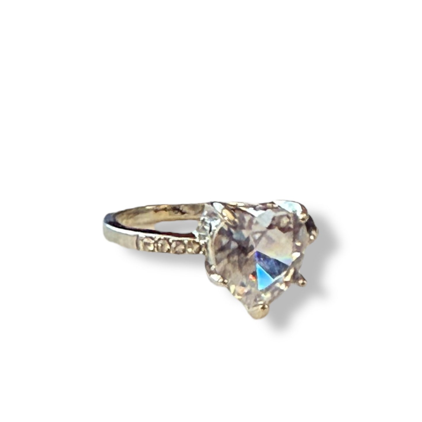 A heart-shaped clear gemstone ring set in a silver-colored metal band with small accent stones on either side, shown on a plain white background.