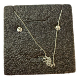 Silver back of necklace and earrings on a textured black surface