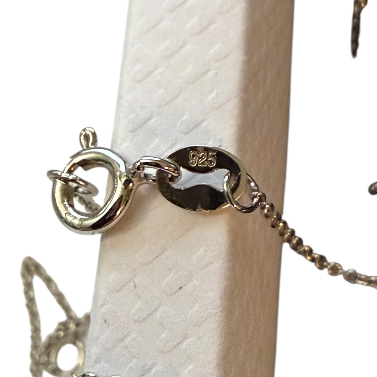 Close-up of a silver necklace 925 with a clasp on a white surface