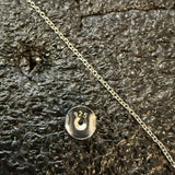 Close-up of a silver chain and earring with a '925' stamp on a textured surface