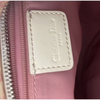 Close-up of a Dior label on a pink bag with a zipper.