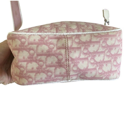 Bottom of pink Dior pattern bag held by a hand on a white background