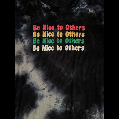 A close-up of a tie-dye dress with a  marbled pattern, featuring the phrase 'Be Nice to Others' printed in a retro rainbow 