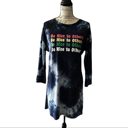 A long-sleeve tie-dye dress displayed on a dress form mannequin against a white background. The dress features a dark blue and light bue tie-dye pattern with a colorful text graphic on the chest that reads 'Be Nice to Others' repeated.