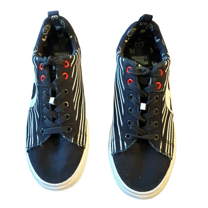 Pair of black and white sneakers with red accents on a white background