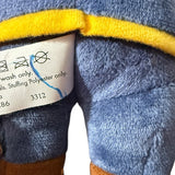 Close-up of a plush toy with a label  and ink mark showing washing instructions.
