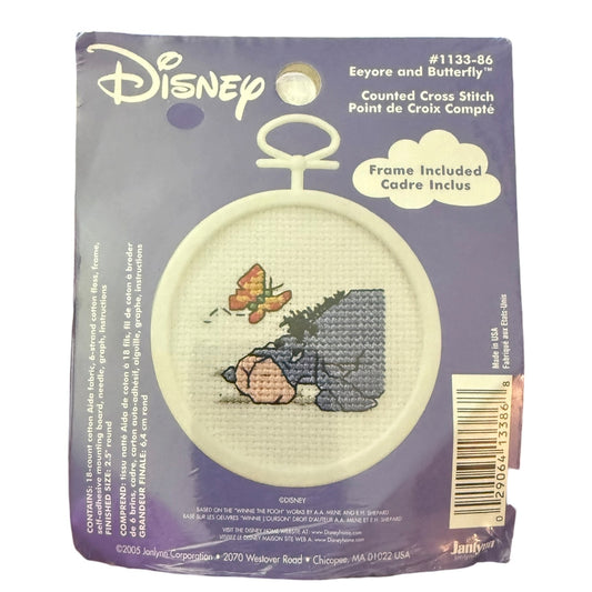 Disney Eeyore and Butterfly counted cross stitch kit in its original purple cardboard packaging, featuring a circular embroidered design of Eeyore and a butterfly.