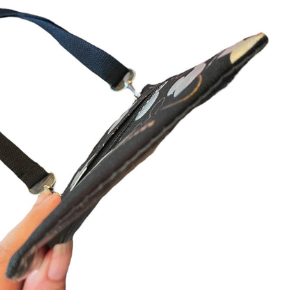 Bottom view of a black bag, held by a hand against a plain white background.