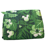 Green floral patterned folded blanket with white flowers on a white background