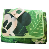 Folded green Mickey Mouse blanket with leaf pattern on a white background