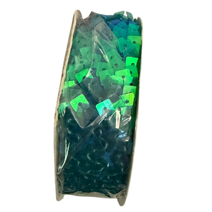 Clear plastic container with green and blue sequins on a white background