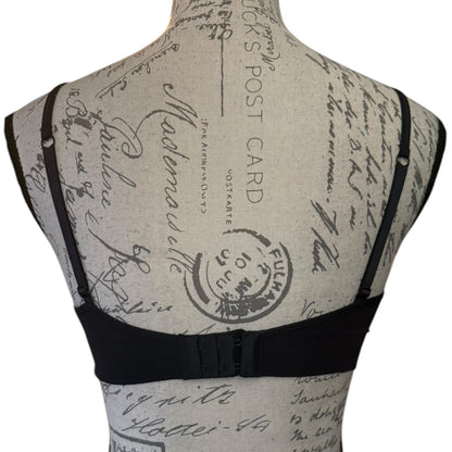 Black bra displayed on a fabric-covered dress form mannequin, showing the back view with adjustable shoulder straps and a center gore.