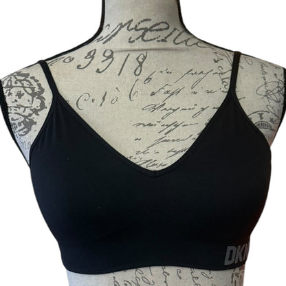 A black V-neck bralette displayed on a beige fabric dress form with cursive writing details, against a plain white background.