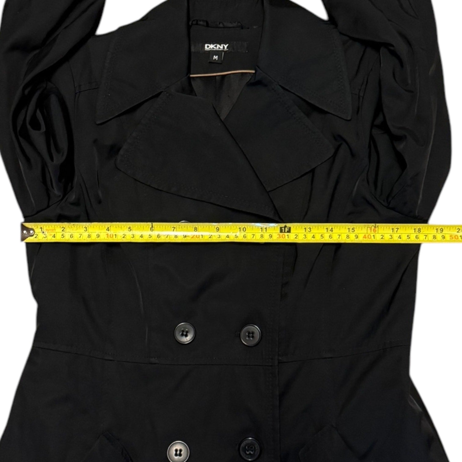 Black coat with a measuring tape across it, featuring the DKNY brand.