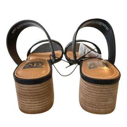 Back of a Pair of open-toe sandals with black straps and tan insoles on a white background