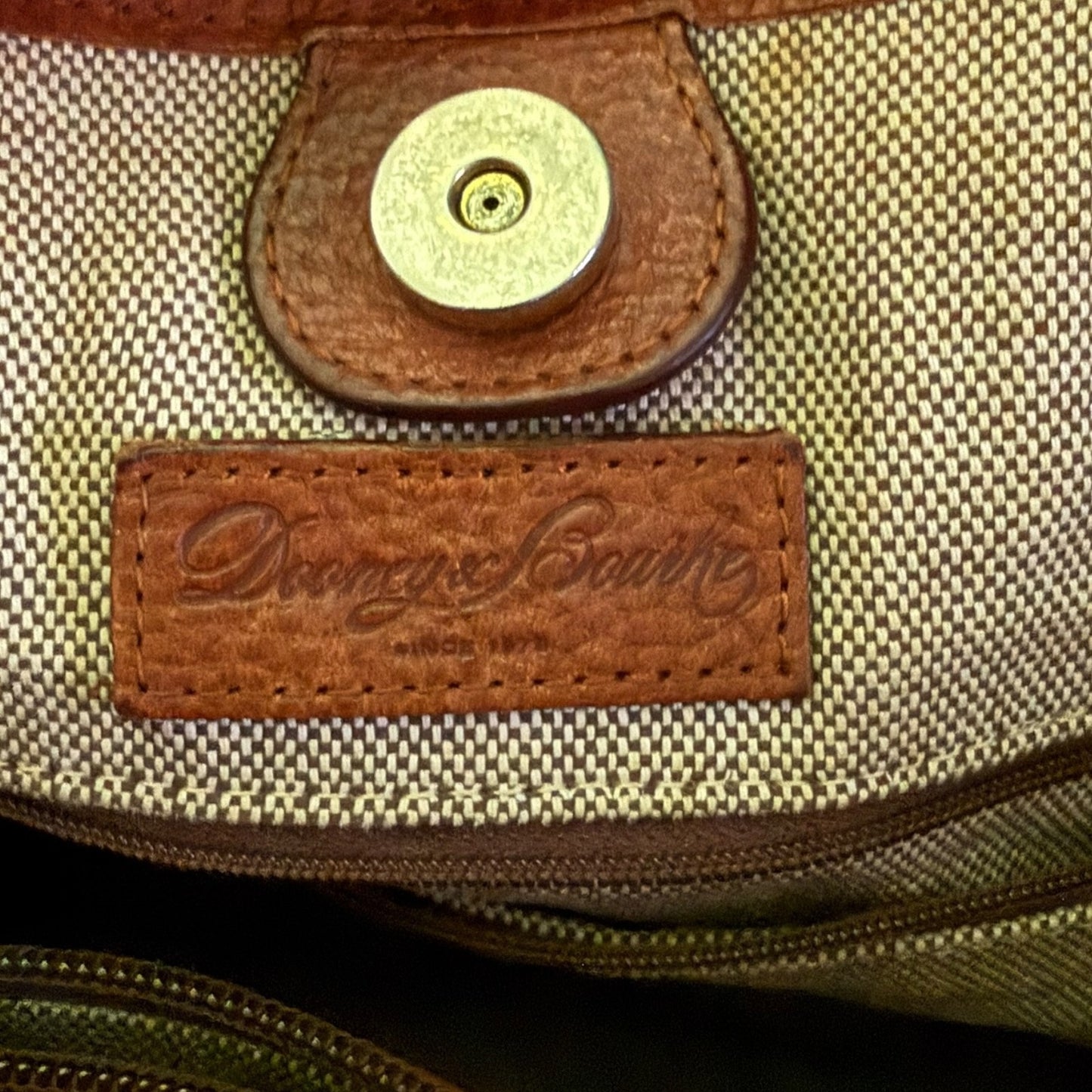 Close-up of a bag with a brown leather label featuring a brand name.