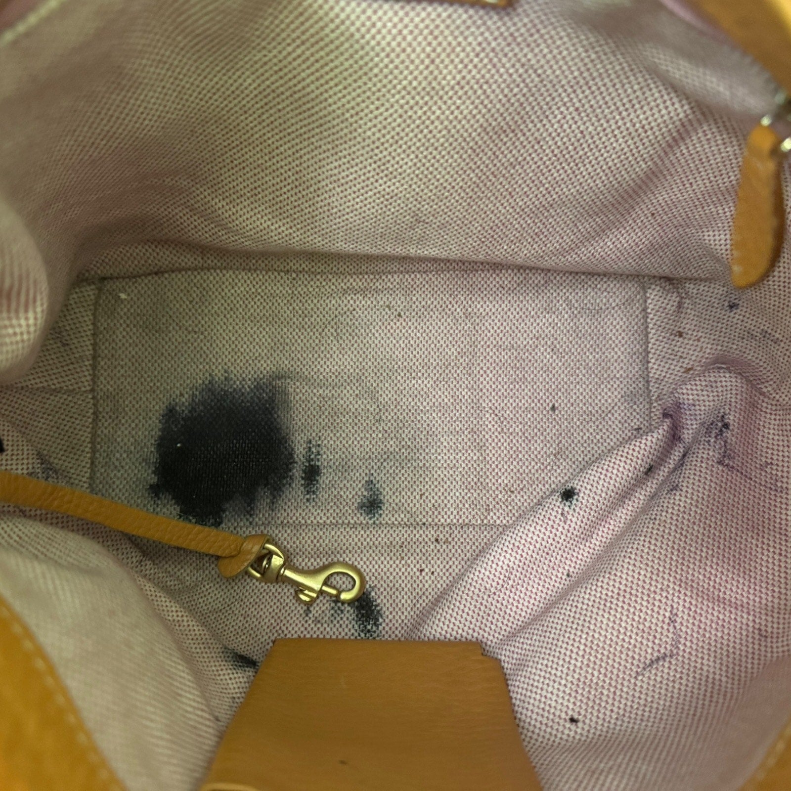 Close-up of a beige bag with brown accents and visible stains.