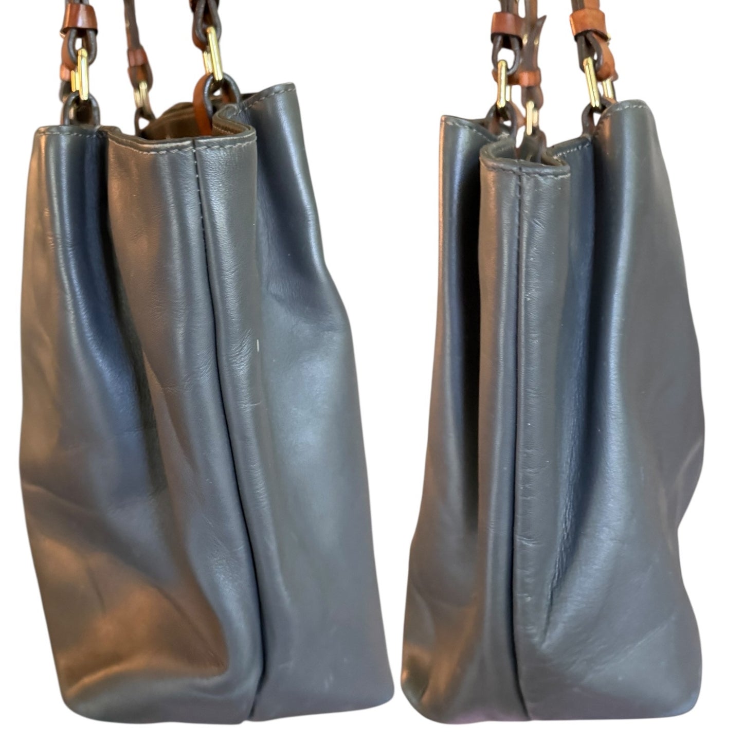 Side view of gray leather handbag with brown handles on a white background