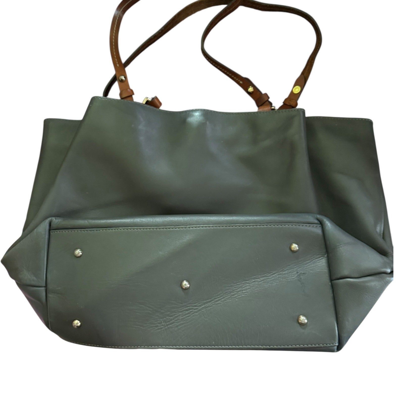 Gray handbag laying down showing bottom with brown handles on a white background