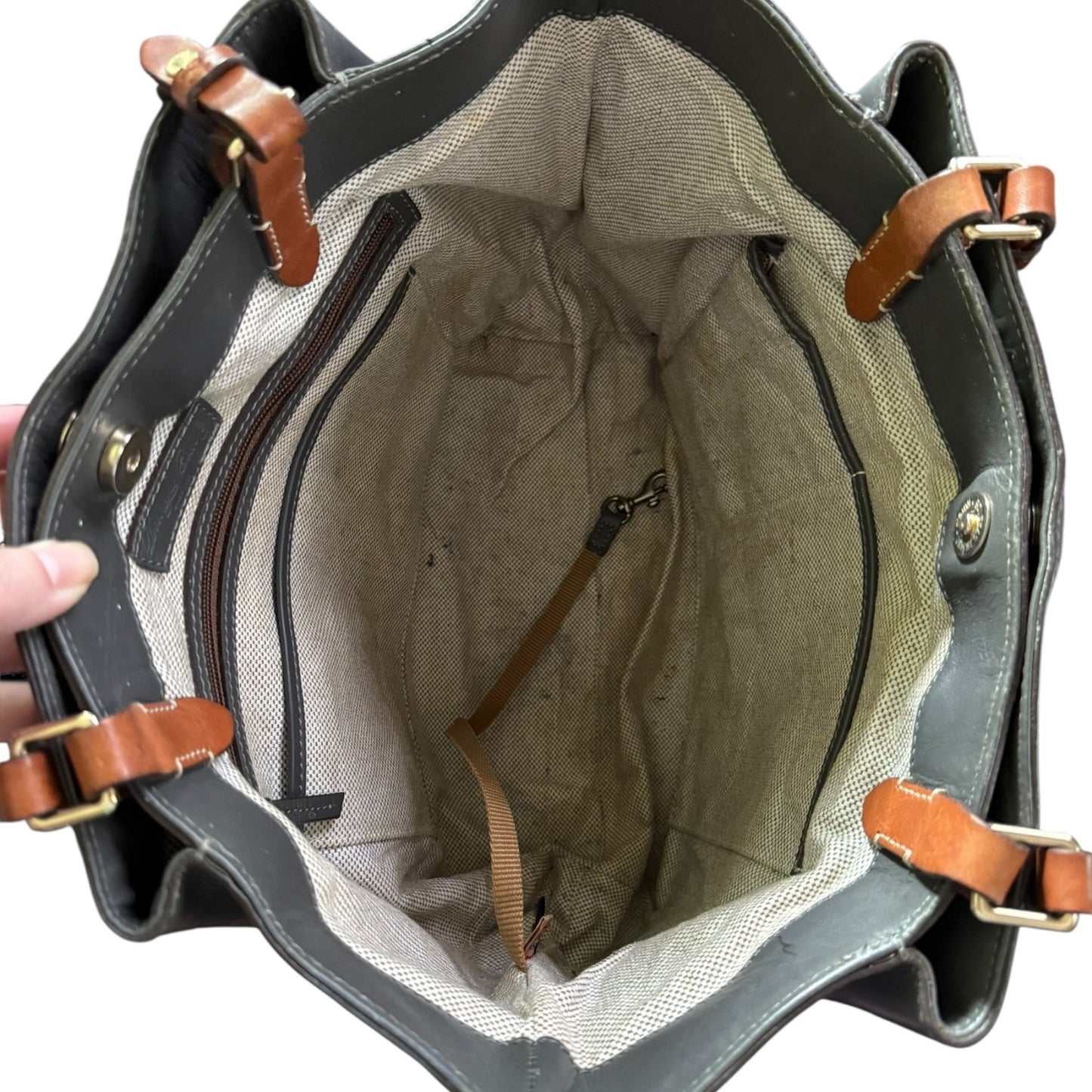 Open leather handbag with brown straps on a white background