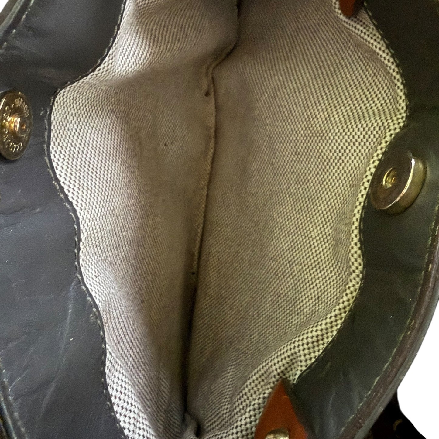 Close-up of a interior of handbag with gold buttons on a dark background