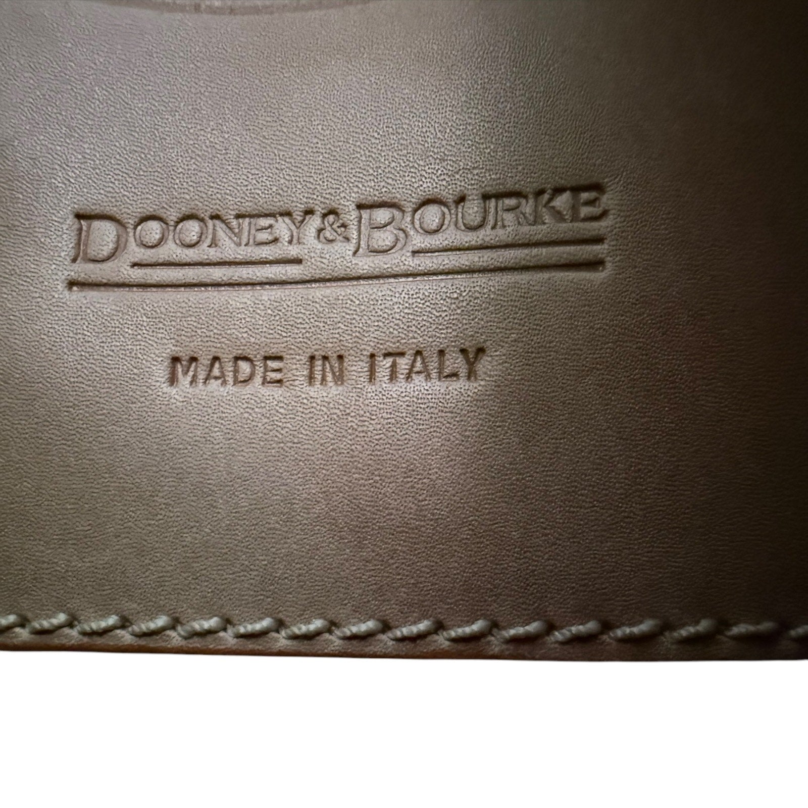 Brown leather surface with 'Dooney & Bourke' and 'Made in Italy' embossed text.