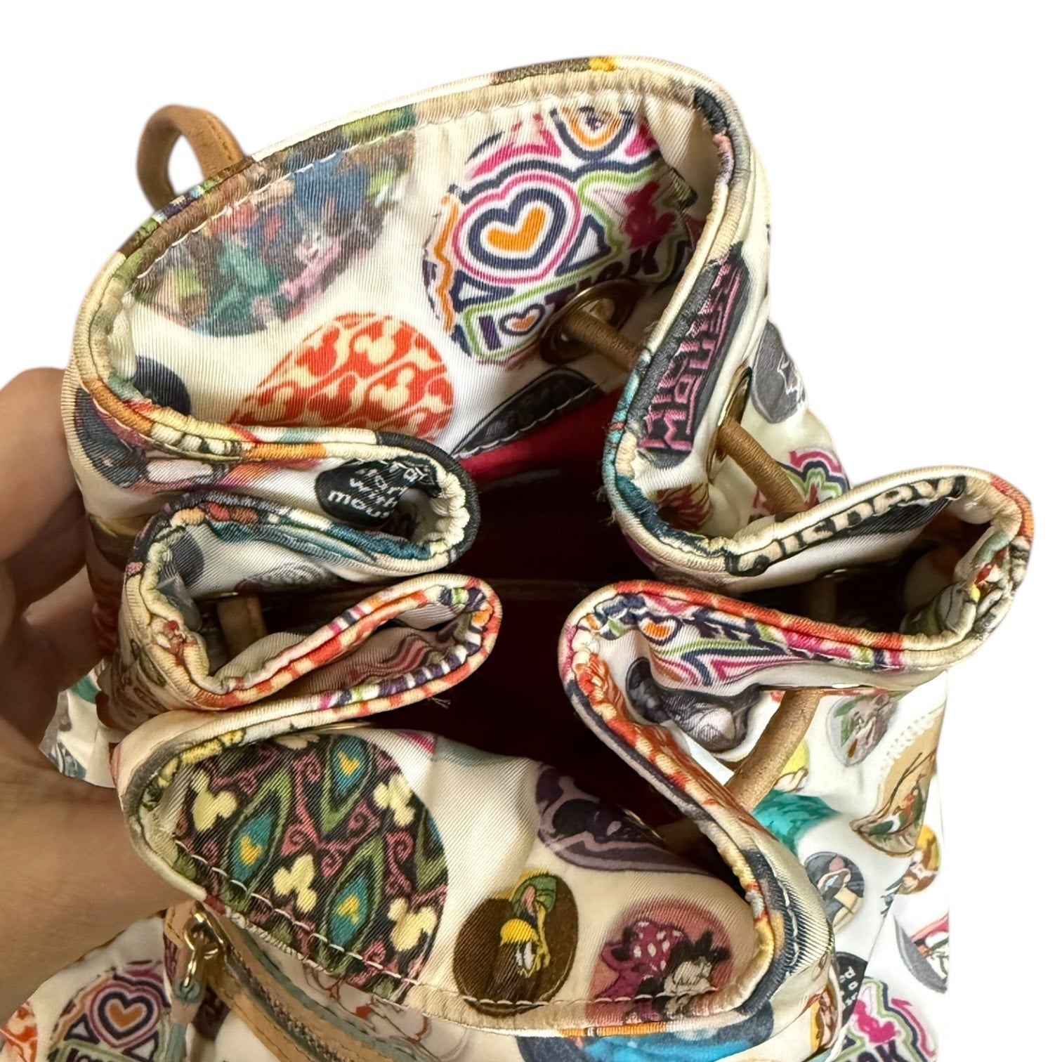 Top closure of Disney backpack held by a hand on a white background
