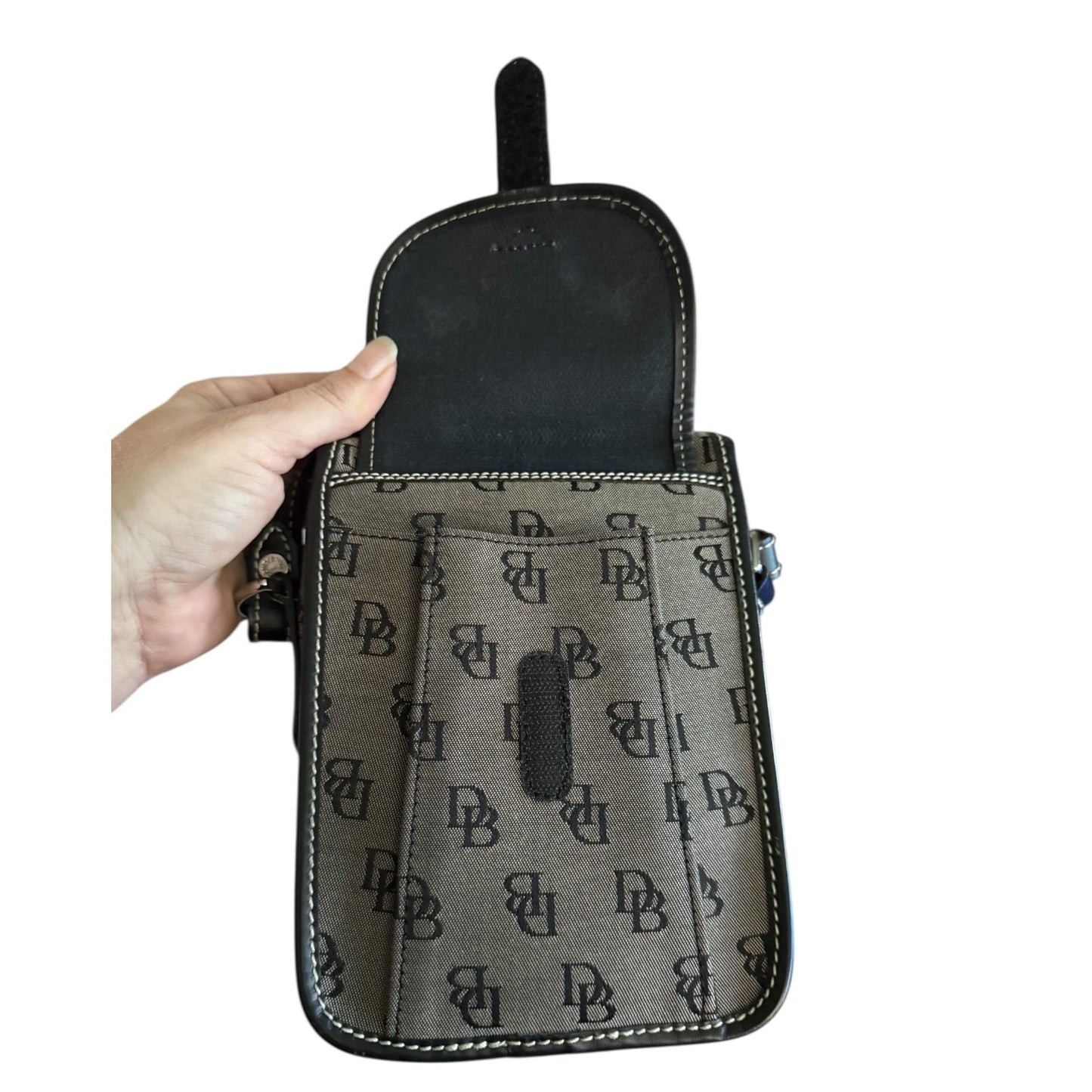 Hand holding a black patterned pouch with visible branding on a white background