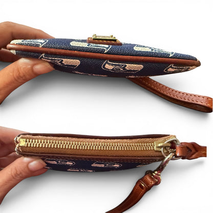 Top and bottom of blue pouch with brown straps and gold zippers held by a hand on a white background. 
