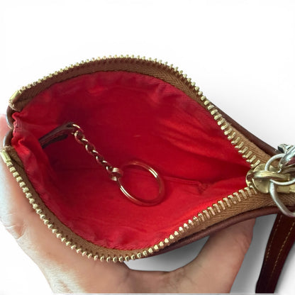 Seahawks pouch with gold zipper and red interior, held by a hand.