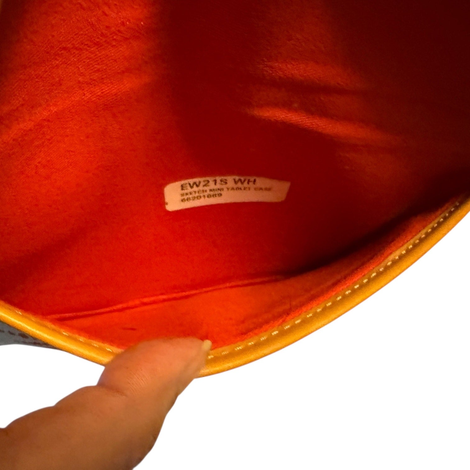 Close-up of a red fabric interior with a label, held by a hand.