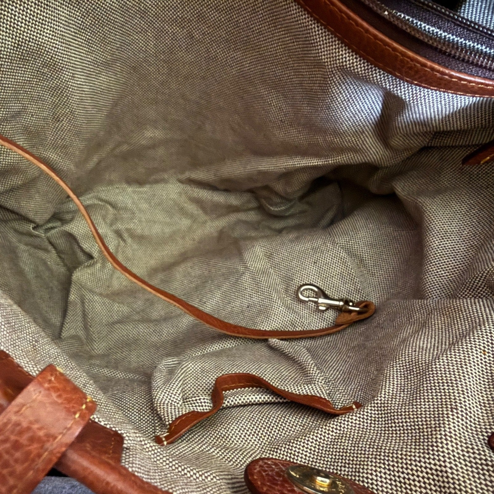 Interior of purse with brown leather bag with a metal clasp on a textured fabric background