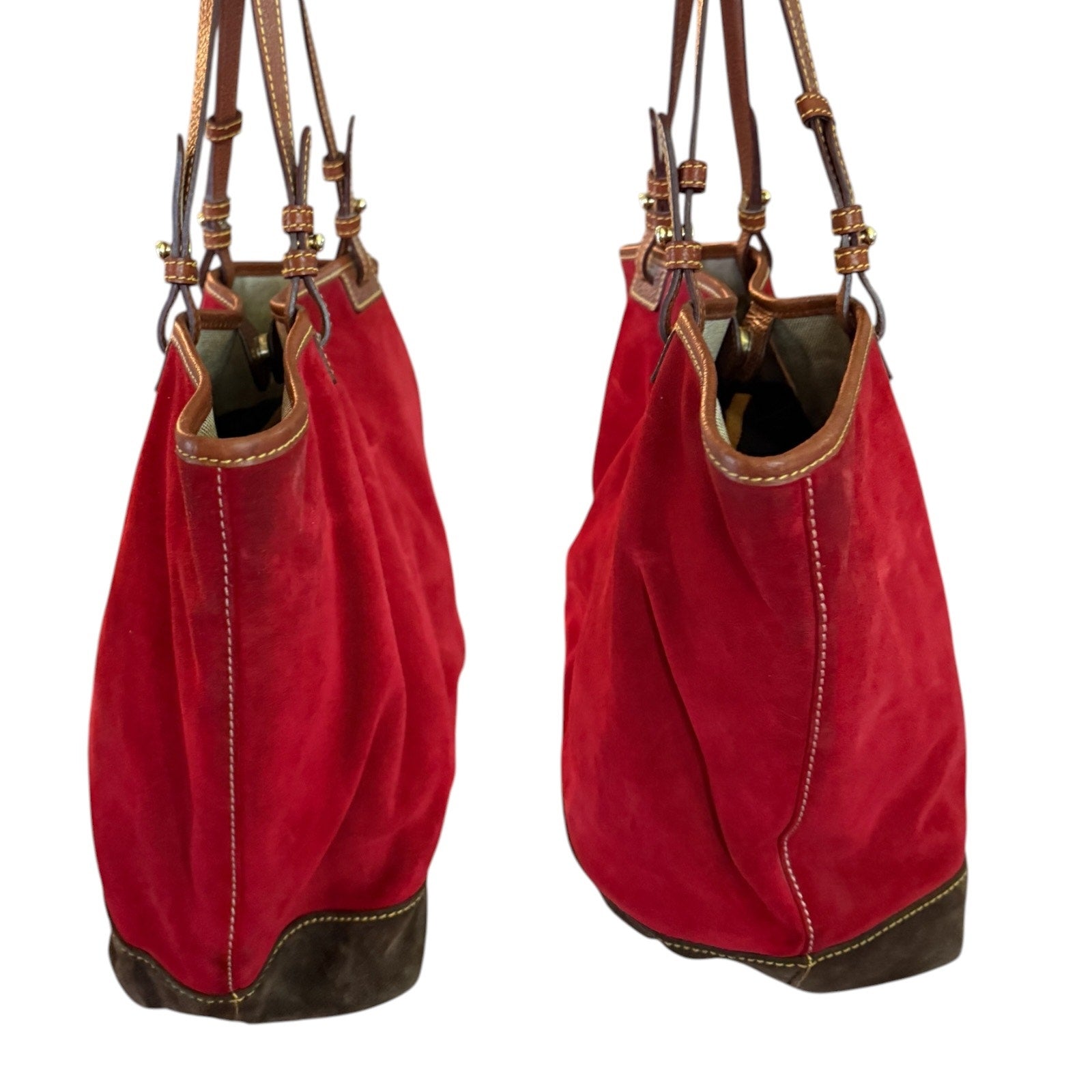 Side view of red suede handbag with brown leather accents on a white background