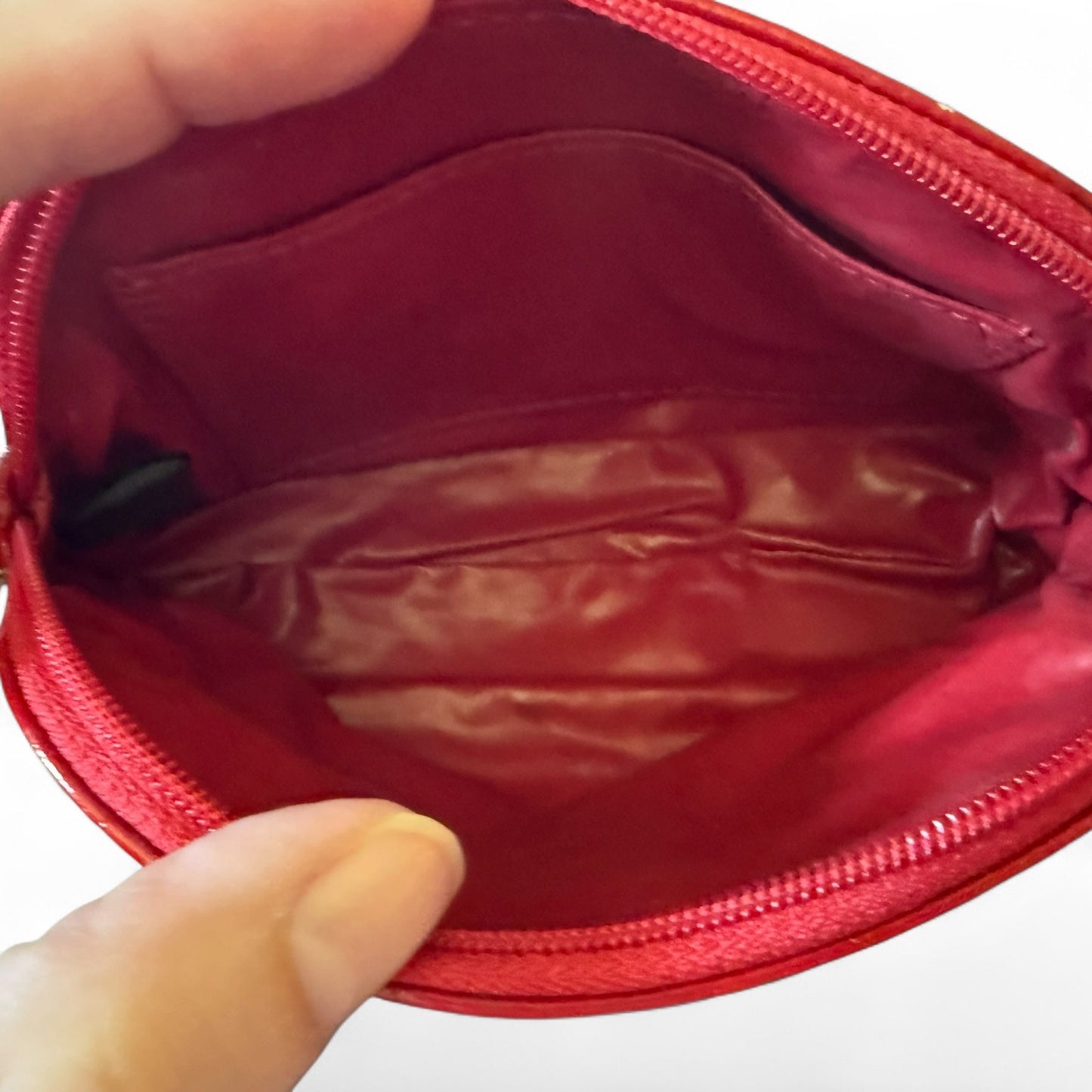 Red pouch held open by a hand on a white background
